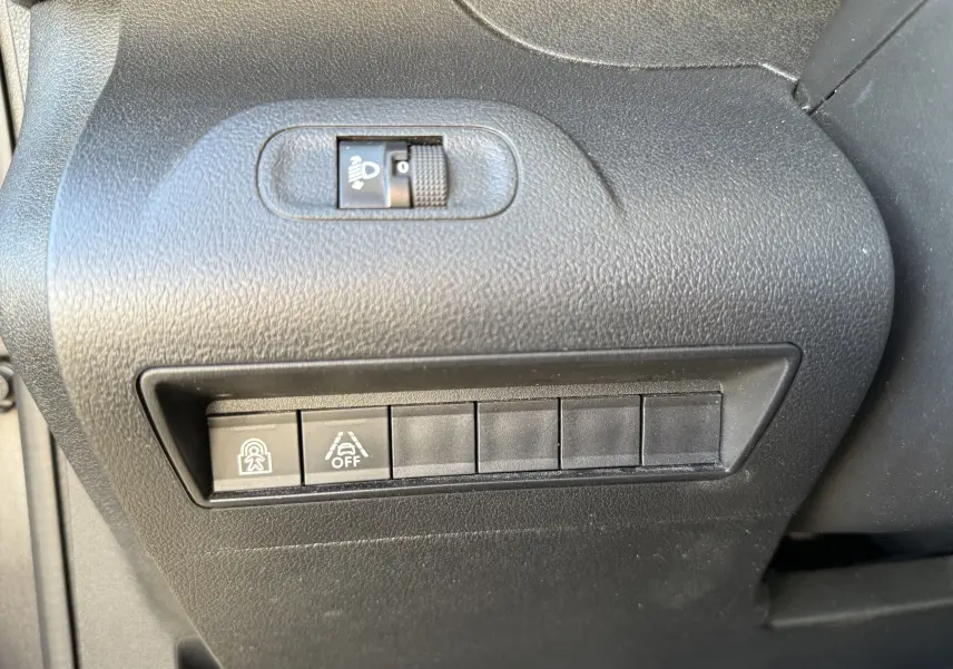 Gros plan sur les commandes de réglage des phares et d'aide à la conduite dans un Peugeot Rifter gris platinium, version 2020.