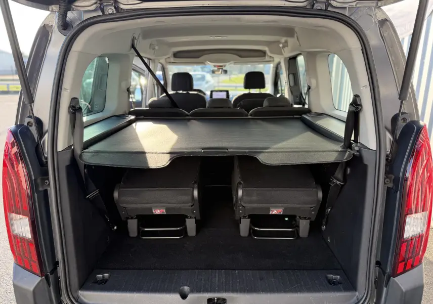 Vue arrière ouverte du Peugeot Rifter gris platinium 2020, montrant le coffre avec cache-bagages et sièges rabattus.