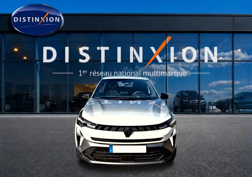 Vue avant d'une Renault Symbioz blanc nacré garée devant une vitrine avec logo Distinxion.
