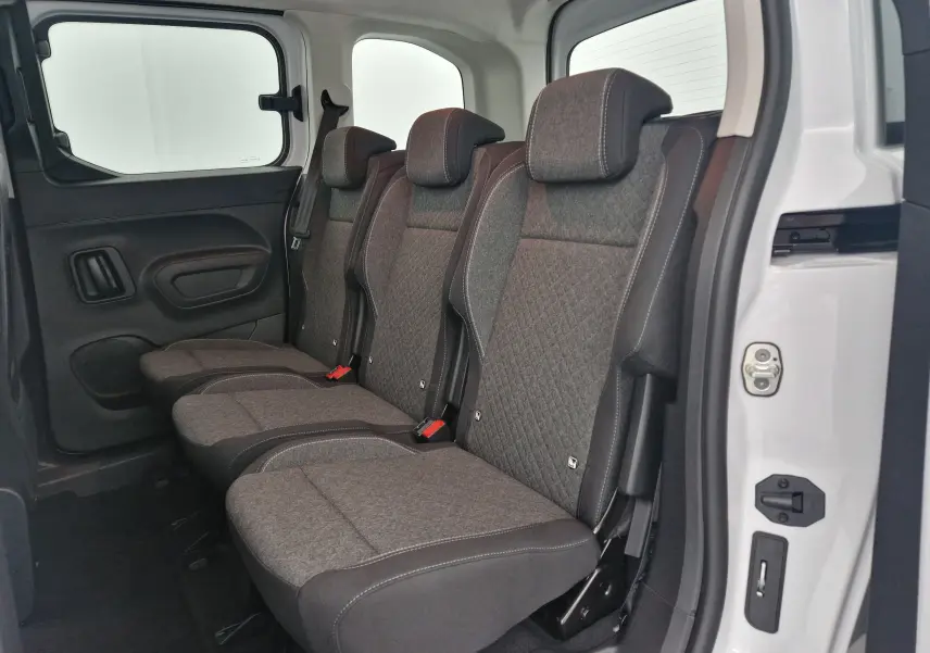 Vue latérale des trois sièges individuels arrière gris foncé de l'Opel Combo Life blanc avec porte coulissante ouverte.