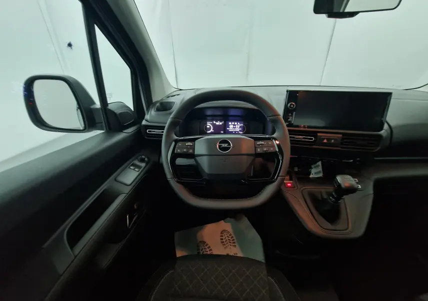 Vue intérieure côté conducteur de l'Opel Combo Life blanc, avec volant multifonction et boîte manuelle visible.