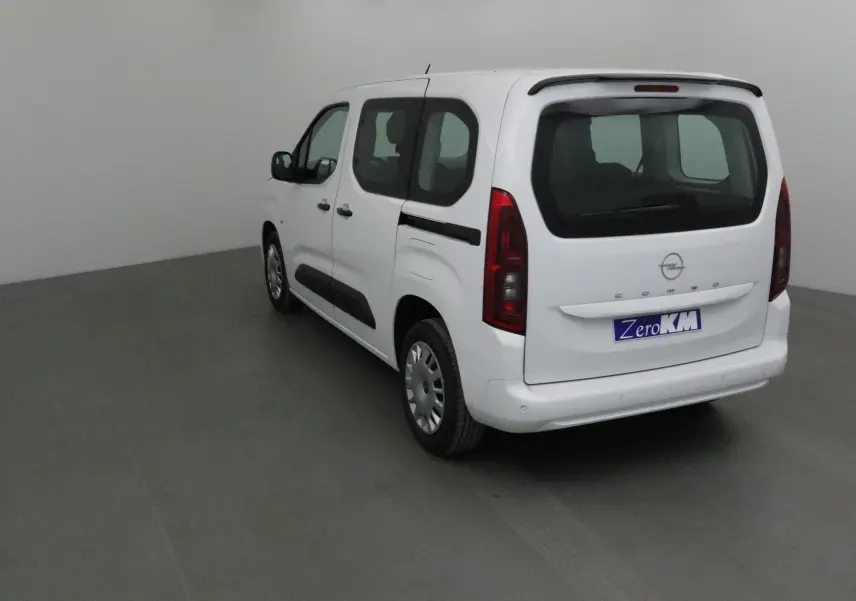 Vue 3/4 arrière droite d'un Opel Combo Life blanc avec becquet et vitres teintées dans un studio.