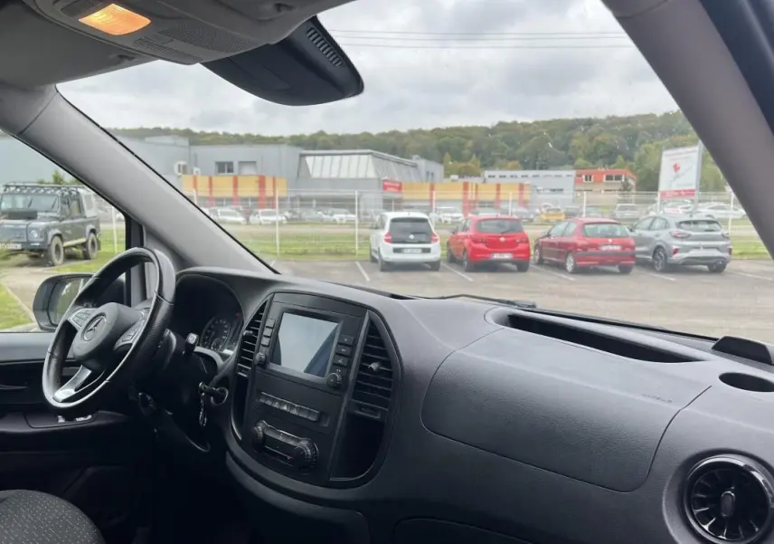 Vue intérieure côté conducteur du Mercedes Vito Fourgon blanc, mettant en valeur le tableau de bord avec écran tactile et volant multifonction.