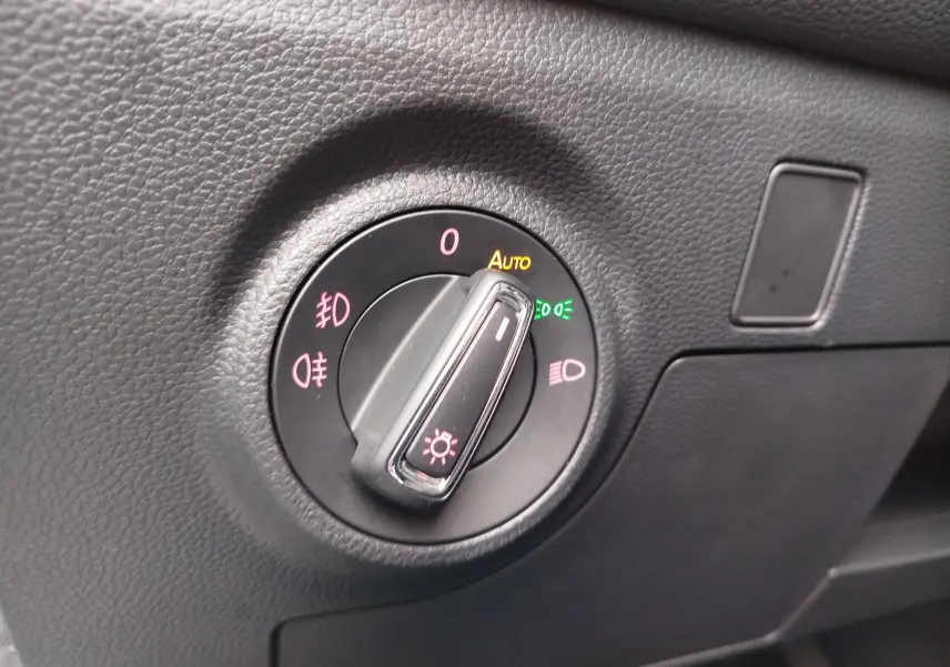 Gros plan sur le sélecteur de phares du tableau de bord en plastique noir texturé d'une SEAT ARONA 2020.