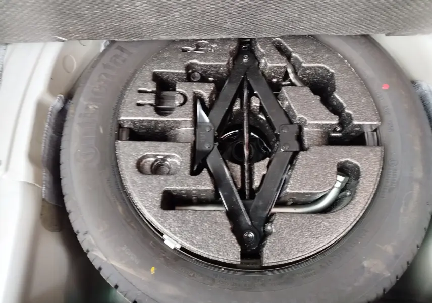 Gros plan sur la roue de secours et le cric noir dans le coffre d’un SEAT Arona blanc avec toit gris.