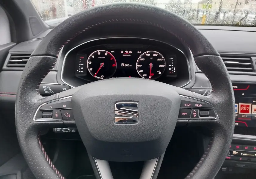 Vue rapprochée du volant en cuir noir avec surpiqûres rouges du tableau de bord d'une SEAT Arona 2020.