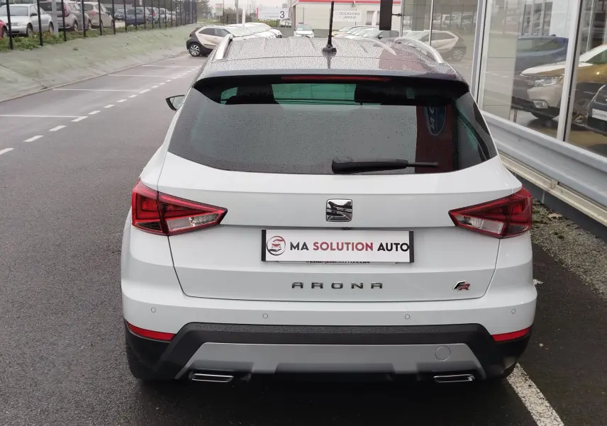 Vue arrière d'un SEAT Arona blanc avec toit gris magnétique, équipé de feux arrière LED et double sortie d'échappement.
