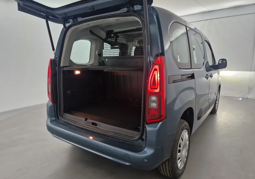 Vue 3/4 arrière droite d'un Opel Combo Life bleu Kiama avec coffre ouvert et grille de séparation visible.