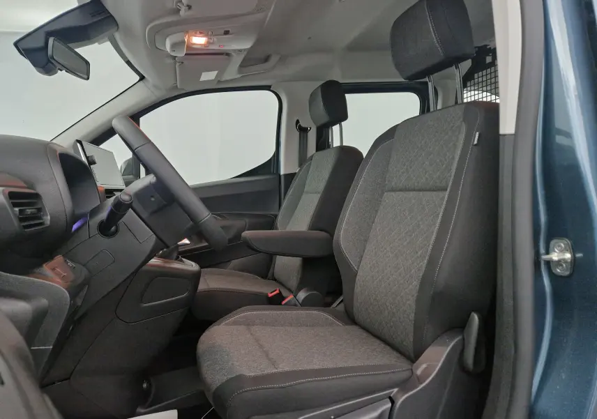 Vue intérieure côté conducteur de l'Opel Combo Life bleu Kiama, sièges tissu gris avec accoudoir et grille de séparation.