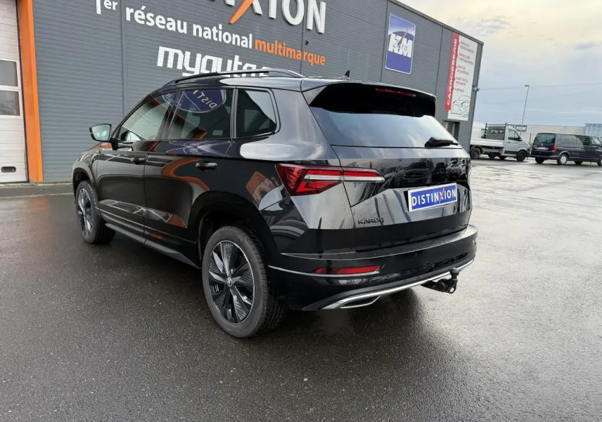 Vue 3/4 arrière droite d'un Skoda Karoq noir magic nacré avec crochet d'attelage et jantes alliage noires.