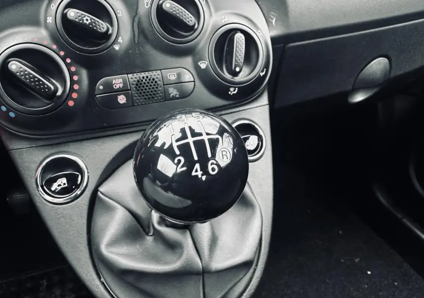 Gros plan sur le levier de vitesses manuel noir et la console centrale grise de la Fiat 500 gris foncé 2023.
