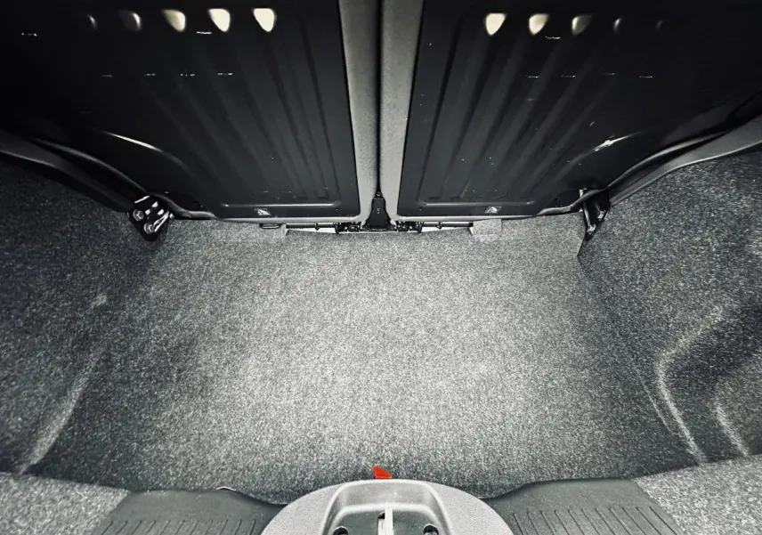 Coffre ouvert vu de face avec banquette arrière rabattue, intérieur gris foncé et tapis de sol gris.