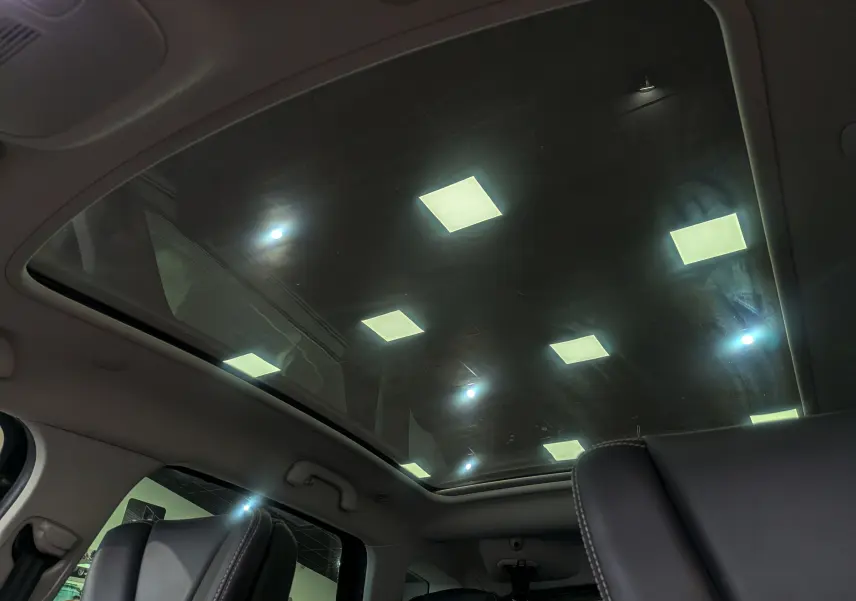 Toit panoramique en verre vu de l'intérieur arrière du Renault Scenic IV Initiale Paris, avec sièges cuir noir visibles.