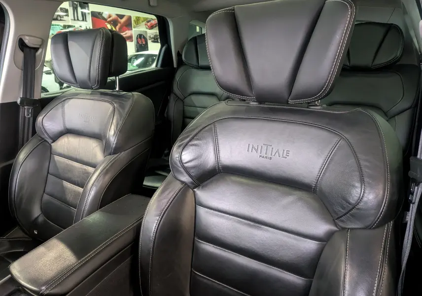 Gros plan sur les sièges avant en cuir noir avec logo Initiale Paris, intérieur du Renault Scenic IV 2018.