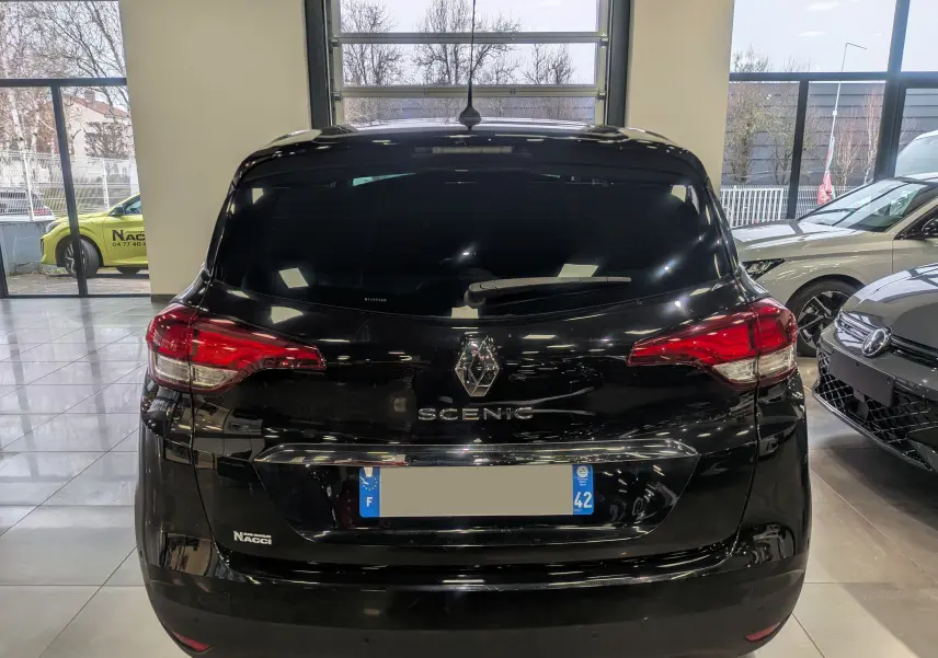 Vue arrière d’un Renault Scénic IV noir étoilé stationné en intérieur avec feux arrière rouges et vitres teintées.