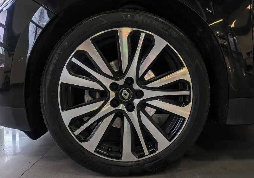 Gros plan sur la jante alliage bicolore du côté avant droit d’un Renault Scénic IV noir étoilé de 2018.