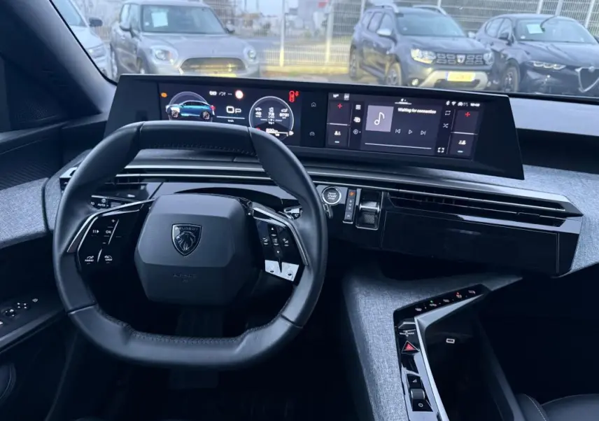 Vue intérieure frontale du cockpit numérique du Peugeot 3008 Hybrid 145 Allure bleu, volant compact et tableau de bord moderne.