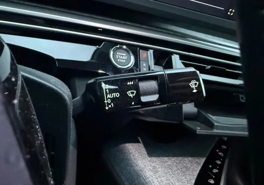 Gros plan sur la commande d’essuie-glace et le bouton start/stop du tableau de bord du Peugeot 3008 Hybrid bleu.