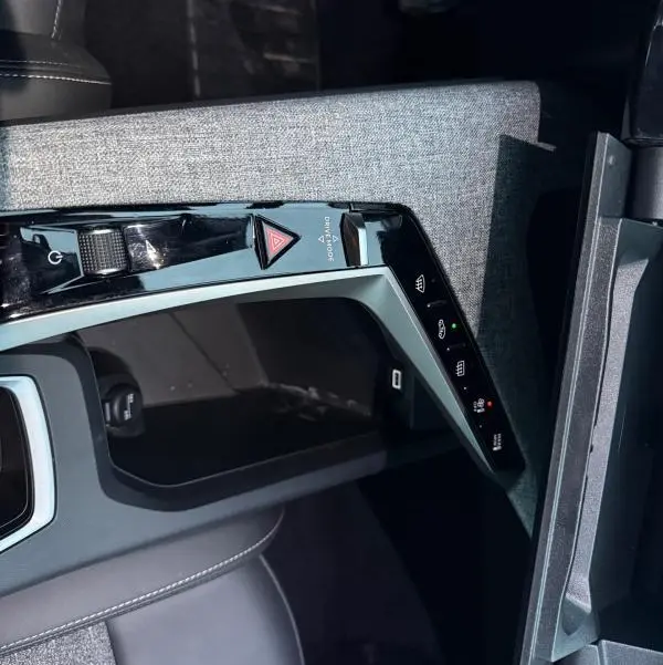 Vue rapprochée de la console centrale du Peugeot 3008 Hybrid 145 e-DCS6 Allure 2025, avec commandes tactiles et finition tissu grise.