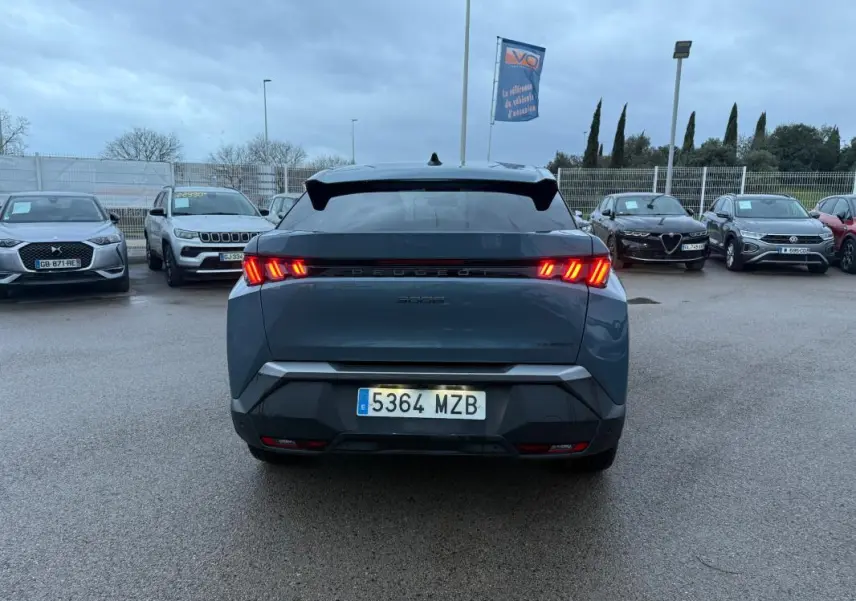 Vue arrière d’un Peugeot 3008 Hybrid bleu 2025 avec feux allumés et jantes alliage 19 pouces sur parking.