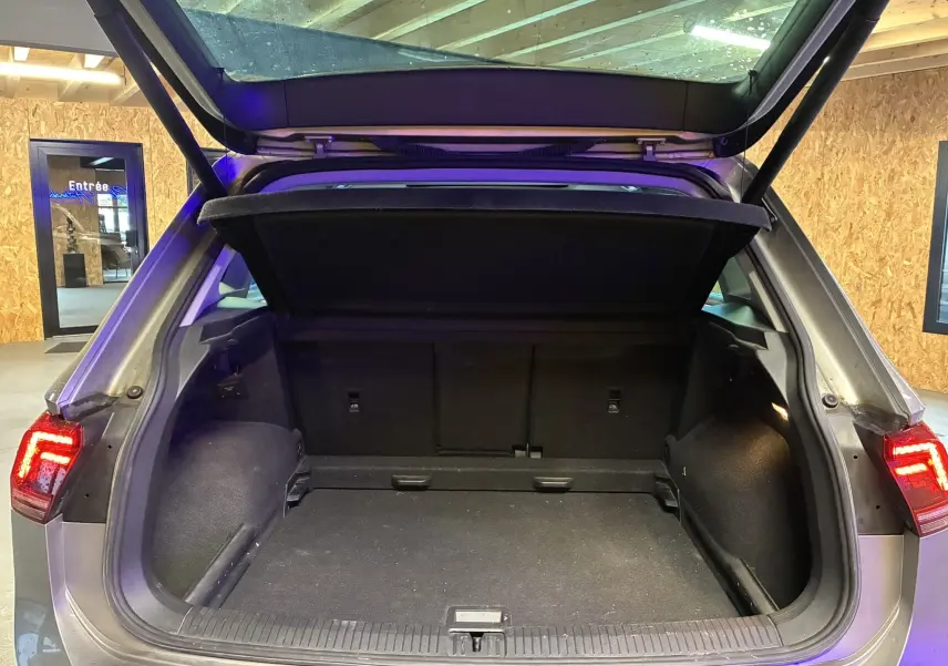 Coffre ouvert vu de l'arrière d'un Volkswagen Tiguan gris 2017, avec hayon et feux arrière allumés.