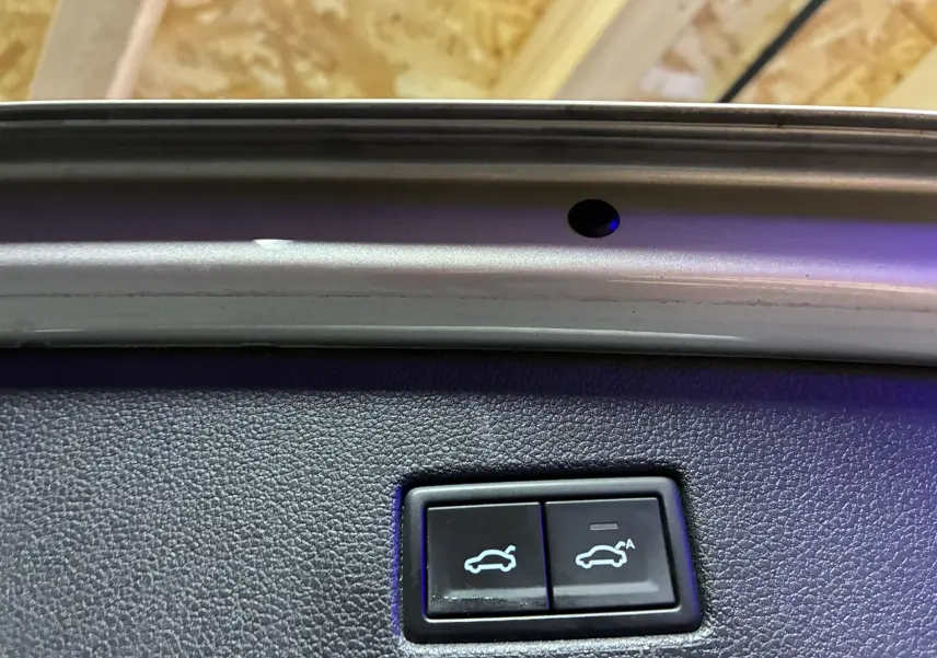 Gros plan sur les boutons d'ouverture et fermeture électrique du hayon intérieur d'un Volkswagen Tiguan gris.