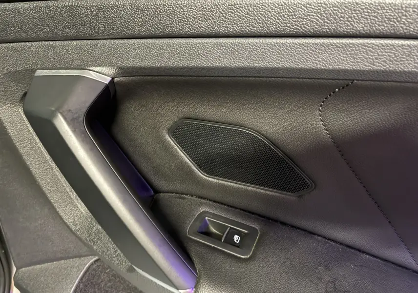 Détail de la portière intérieure côté gauche du Volkswagen Tiguan 2.0 TDI 150 Carat 2017 avec bouton de commande de vitre et haut-parleur intégré.
