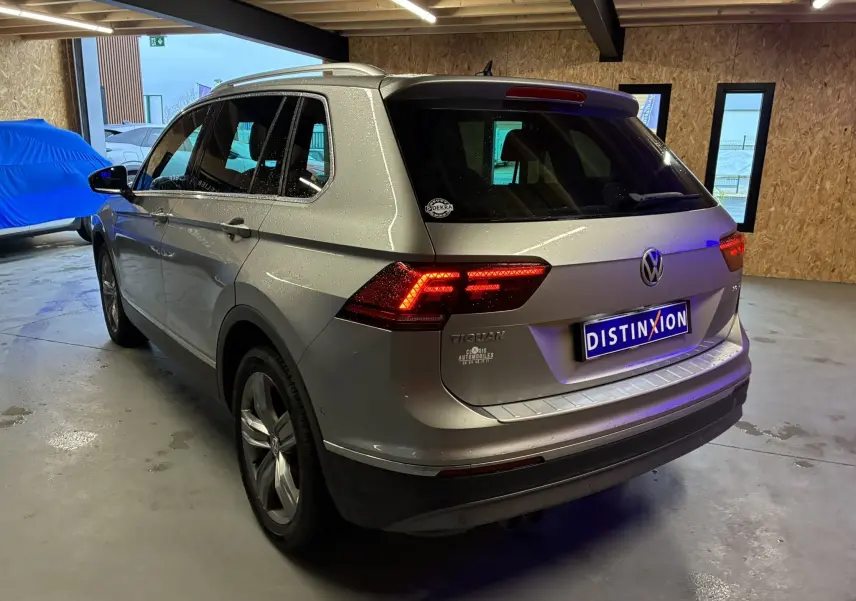 Vue 3/4 arrière droite d’un Volkswagen Tiguan gris 2017 avec feux arrière allumés dans un garage.