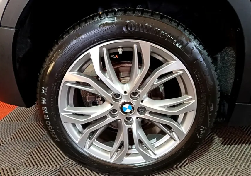 Gros plan sur la roue arrière droite d’un BMW X2 gris foncé, mettant en valeur le pneu Continental et l’arche de roue.