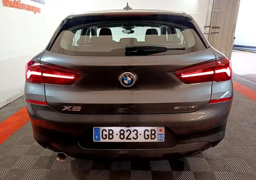 Vue arrière d’un BMW X2 sDrive18i gris foncé avec feux LED allumés et plaque d’immatriculation française visible.