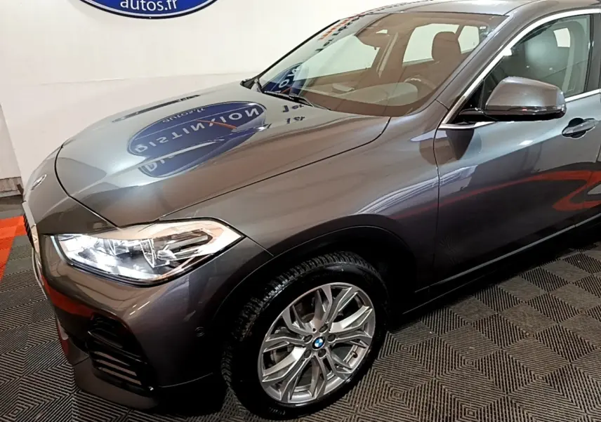 Vue 3/4 avant droit d’un BMW X2 sDrive18i Lounge gris foncé avec phares LED et jantes alliage visibles.
