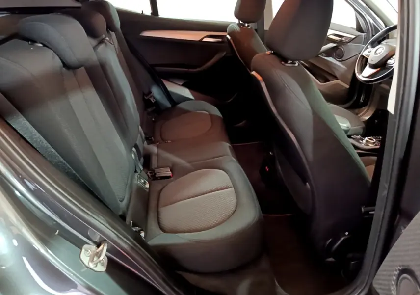 Vue intérieure côté gauche montrant les sièges arrière noirs et l'avant du BMW X2 sDrive18i Lounge DKG7 gris foncé.