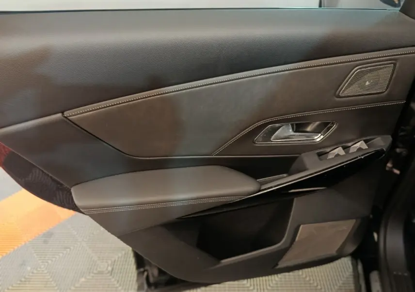 Vue rapprochée de la porte intérieure côté gauche en cuir noir avec surpiqûres blanches et haut-parleur intégré du DS7 Crossback E-TENSE 2022.