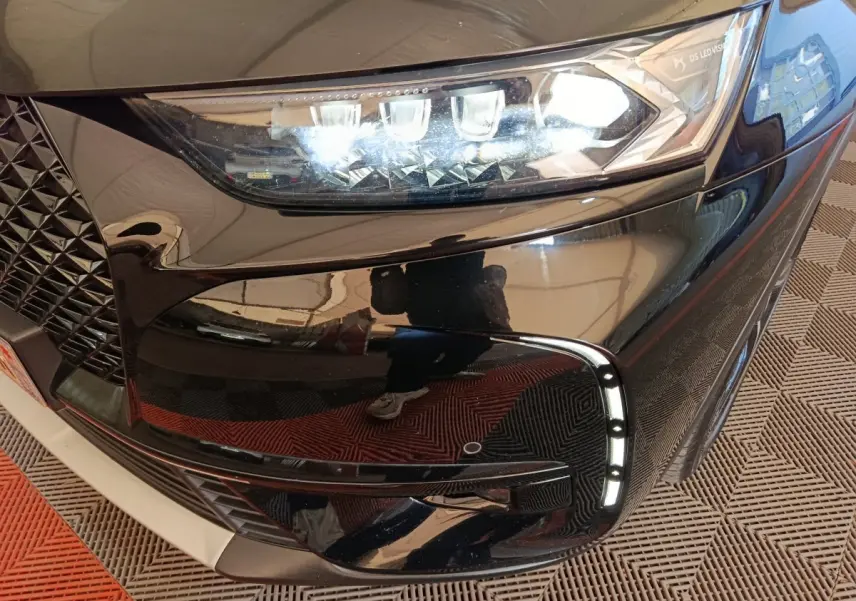 Gros plan sur le phare avant droit noir brillant du DS7 Crossback E-TENSE 4x4 300 LOUVRE avec feux LED et détails chromés.