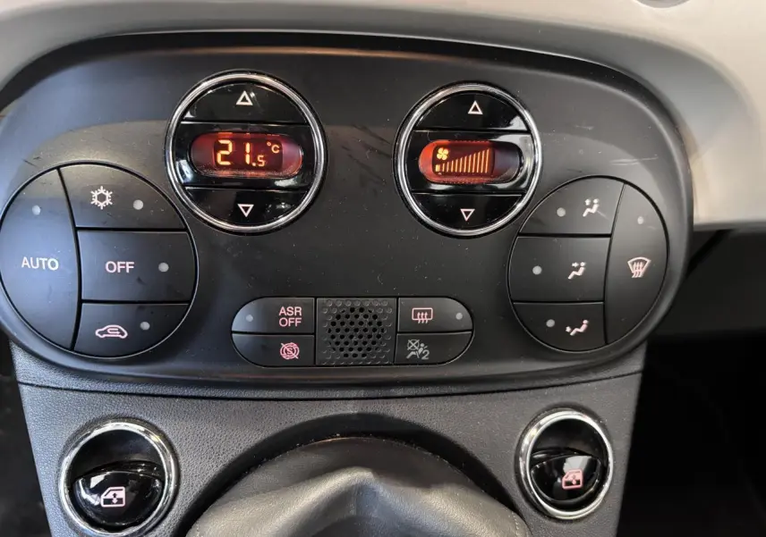 Gros plan sur la console de climatisation automatique de la Fiat 500, avec affichage numérique et commandes circulaires.