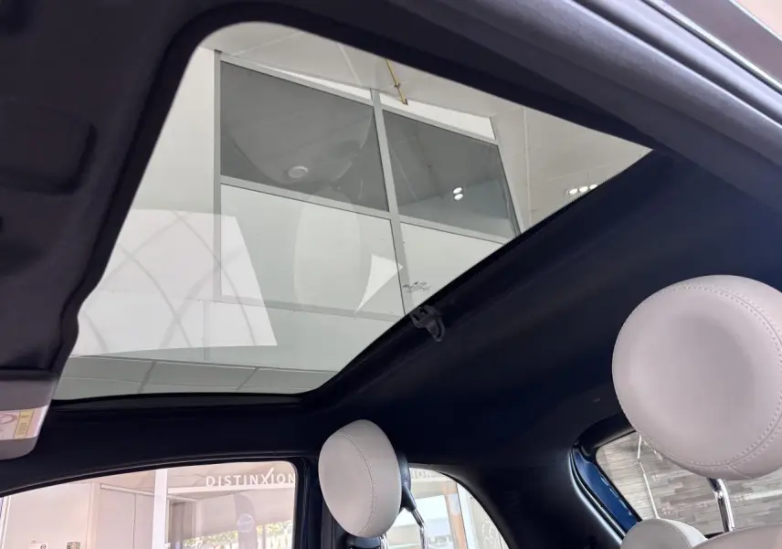 Vue intérieure du toit vitré panoramique fixe de la Fiat 500 vert, avec appuie-têtes avant gris clair visibles.