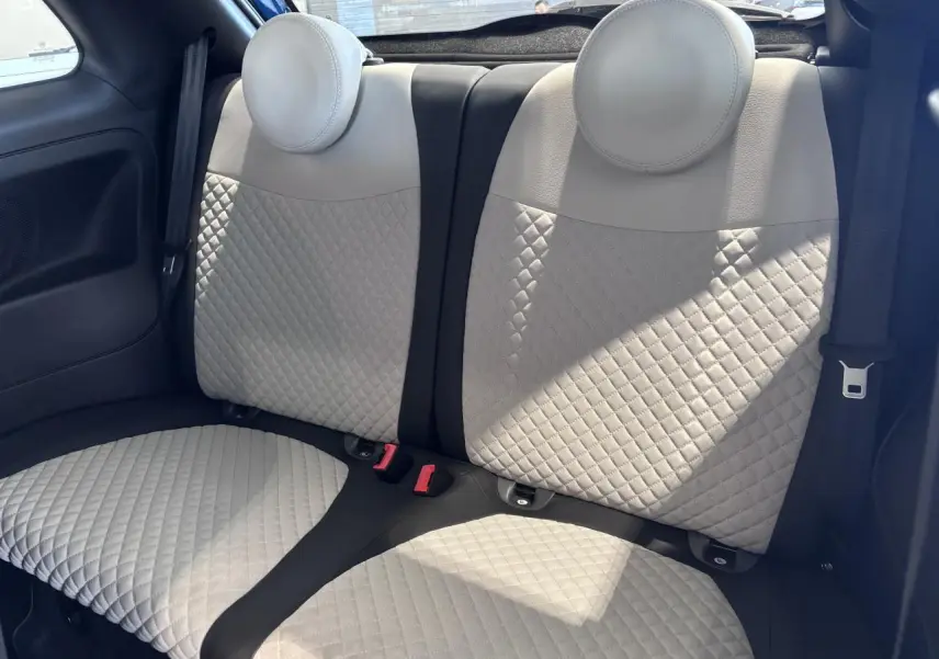 Vue intérieure sur la banquette arrière beige matelassée de la Fiat 500, avec ceintures de sécurité visibles.