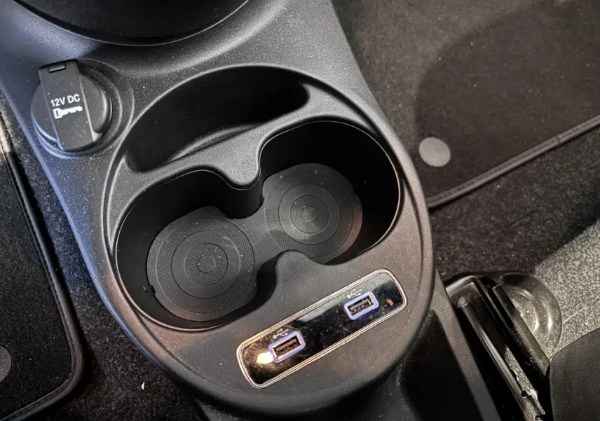 Gros plan sur la console centrale avec porte-gobelets et deux ports USB de la Fiat 500 verte de 2021.