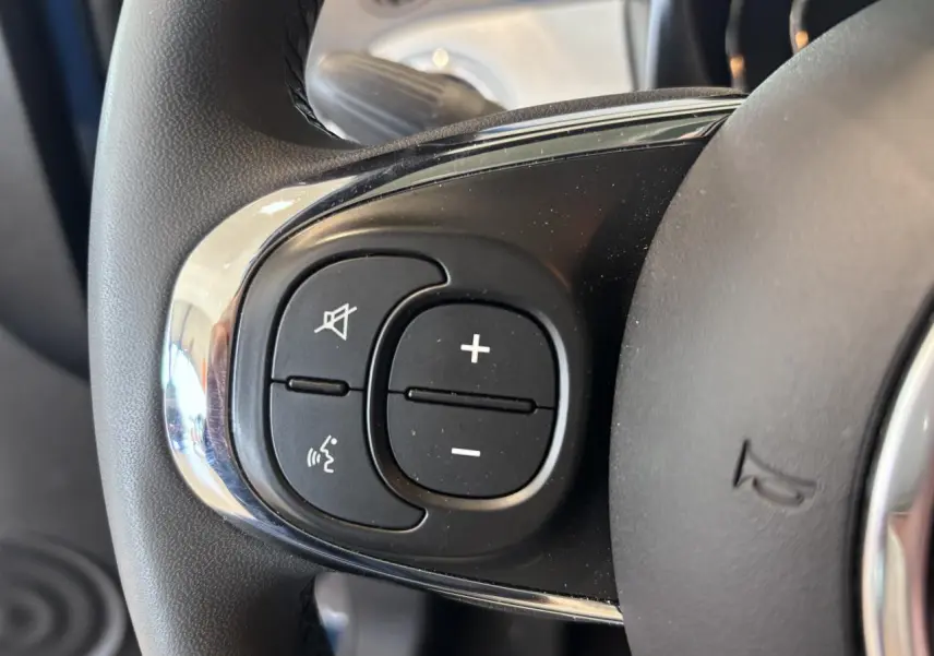 Gros plan sur les commandes de volume et de coupure du son au volant de la Fiat 500, finition Dolcevita.
