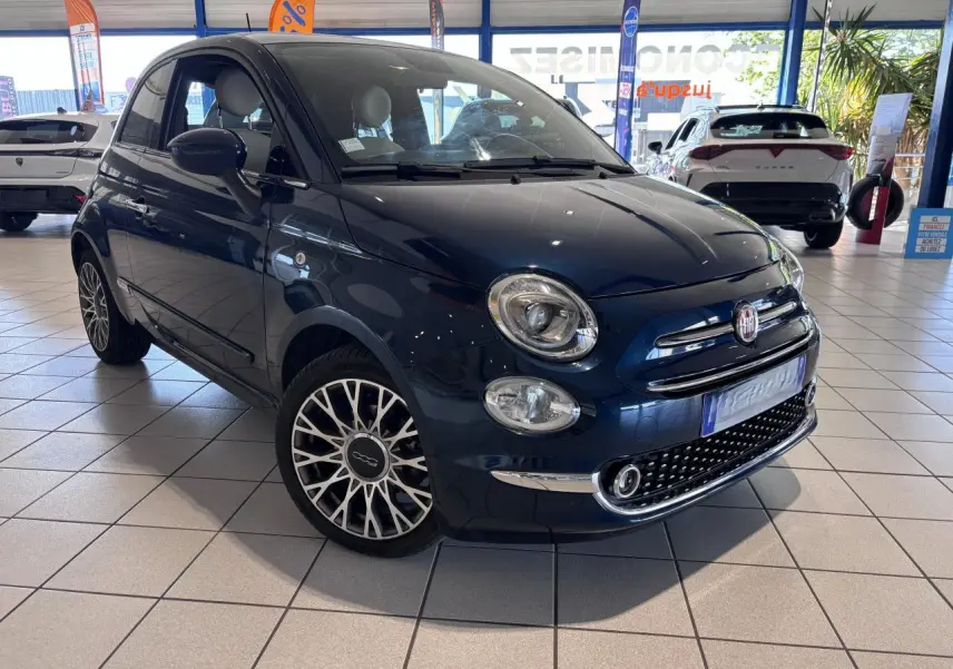 Fiat 500 bleu foncé vue 3/4 avant droit en showroom, avec jantes alliage et calandre chromée.