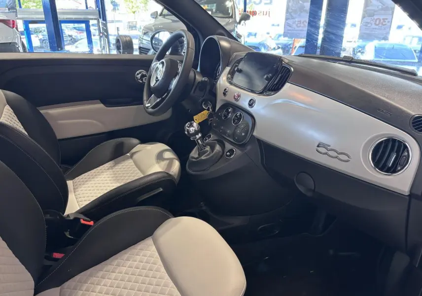 Vue intérieure côté conducteur de la Fiat 500 avec sellerie bicolore et tableau de bord blanc brillant.