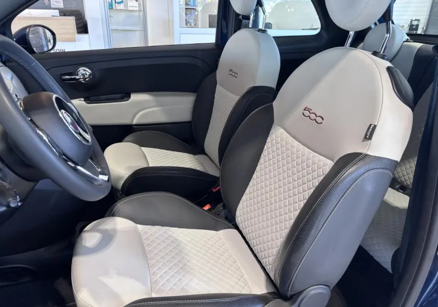 Vue intérieure côté conducteur de la Fiat 500 avec sièges bi-ton beige et noir matelassés et logo 500 brodé.