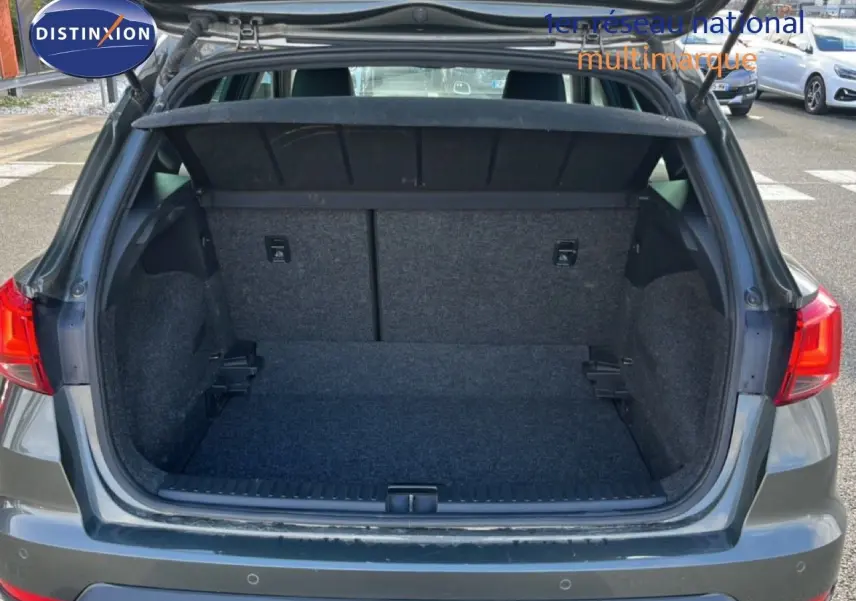 Coffre ouvert vu de l'arrière d'un SEAT Arona gris métallique, montrant un espace de chargement vide et propre.