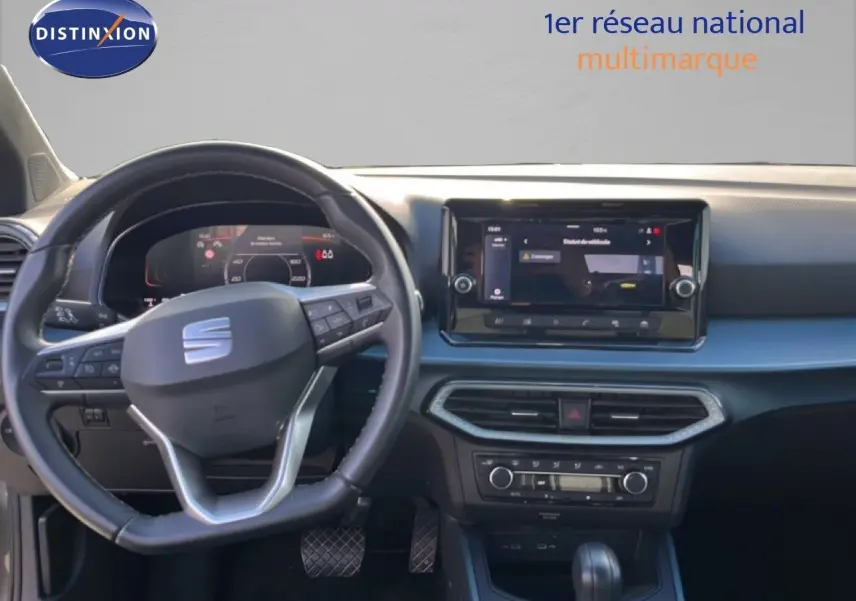 Vue intérieure du tableau de bord et volant noir du SEAT Arona gris magnétique, avec écran tactile central et commandes au volant.