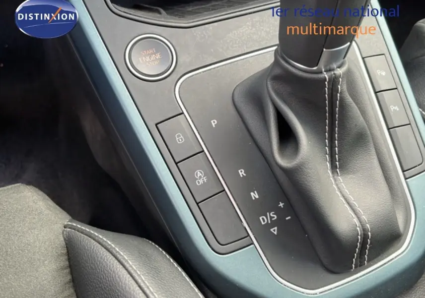 Gros plan sur la console centrale de la SEAT Arona 2025, boîte auto avec levier cuir et bouton start/stop, finition gris métallique.