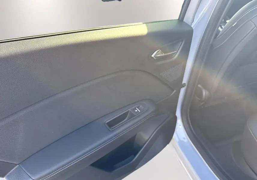 Vue intérieure du panneau de porte arrière gauche gris clair avec accoudoir noir et bouton de vitre électrique.
