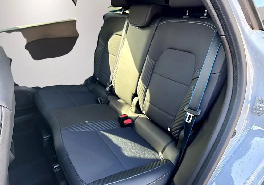 Vue intérieure sur la banquette arrière noire avec surpiqûres bleues du Renault Symbioz gris rafale, porte ouverte côté droit.