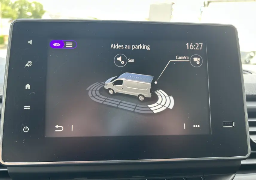 Écran tactile intérieur montrant l'aide au parking du Renault Trafic fourgon blanc en vue latérale droite.