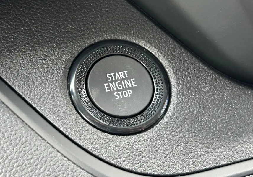 Gros plan sur le bouton Start Engine Stop noir intégré dans la console intérieure du Renault Trafic Fourgon blanc.