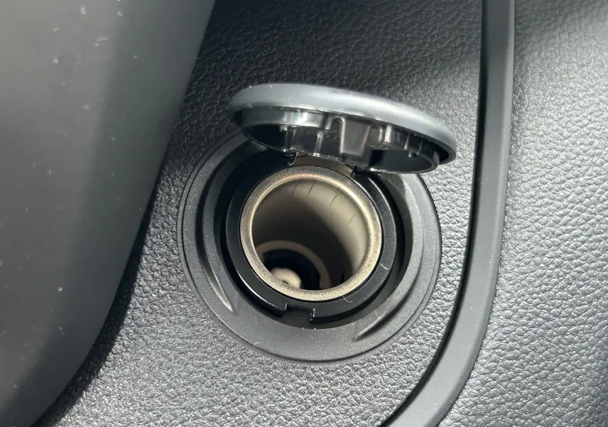 Gros plan sur la prise allume-cigare noire intégrée dans la console intérieure du Renault Trafic Fourgon blanc.